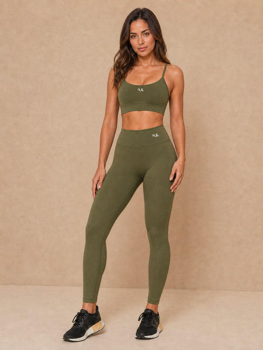 Modelo vestindo conjunto fitness feminino com top e legging de compressão em fundo bege.